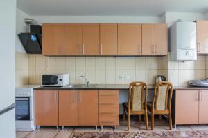 eine Küche mit Holzschränken, einer Spüle und 2 Stühlen in der Unterkunft Rooms with Fortetsya View 2 in Kamjanez-Podilskyj