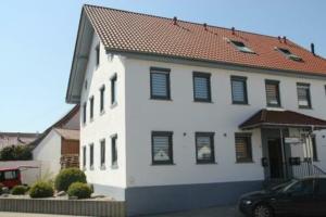 a white house with a car parked in front of it at Pension zum Hecht in Schemmerberg