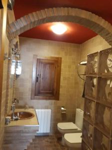 a bathroom with a toilet and a sink and a wooden door at Finca Los Villegas in Castril