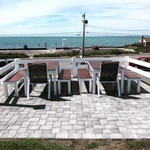 een picknicktafel en stoelen met de oceaan op de achtergrond bij Oceanside Condos in Dennis Port