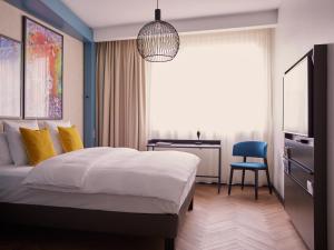 a bedroom with a bed and a desk and a chair at Hotel Mondial am Dom Cologne MGallery in Cologne