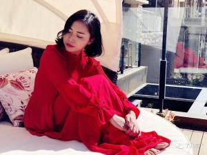 uma mulher de vestido vermelho sentada numa cama em Dali Liao Fan Seaview Villa em Dali