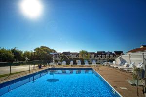 a large swimming pool with lounge chairs at Village By The Sea in Wells