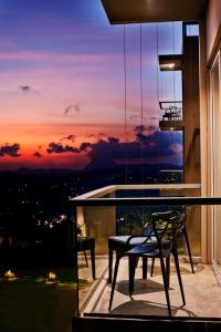 a glass table and chairs on a balcony with a sunset at Skyloft Kandy by Aaradhya in Kandy