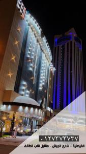 un gran edificio con una noria delante de él en Borj Al Thahabiah ApartHotel, en Taif