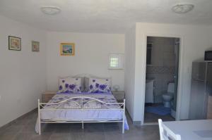 a bedroom with a purple bed and a bathroom at Studio Apartment Mileta in Pitve