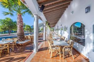 un patio esterno con tavoli, sedie e una palma di Ona Garden Lago a Port d'Alcudia