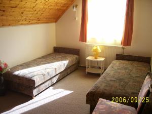 a bedroom with two beds and a window and a table at Fanni Guest House in Balatonvilágos