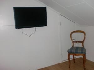 um quarto com uma cadeira e uma televisão na parede em Trollhättans Bed and Breakfast em Trollhättan
