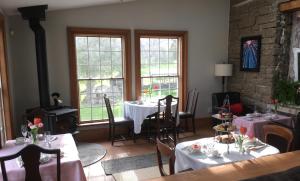 a dining room with two tables and two windows at Harlem Stonegate B&B in Portland