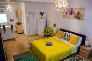 a bedroom with a yellow bed and a green chair at Collosal Studio in Bucharest