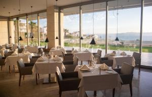 a restaurant with white tables and chairs and large windows at ON'LIVE HOTEL in Çeşme