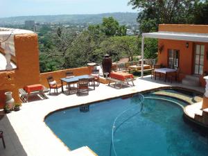 a swimming pool with chairs and a table next to a house at Villa Valencia in Pinetown