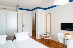 Cette chambre comprend un lit, une table et une télévision. dans l'établissement Aparthotel Adagio Access Strasbourg Illkirch, à Illkirch-Graffenstaden