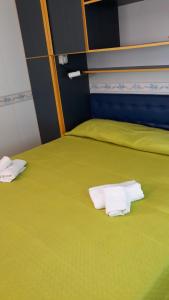 2 Betten in einem Zimmer mit grüner Bettwäsche und Handtüchern in der Unterkunft VILLAGGIO STAGNONE in Marsala