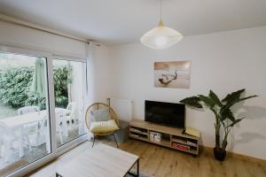 een woonkamer met een tv en een tafel bij Appartement 4 personnes jardin et parking in Vannes