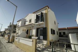 a white house with black shutters on a street at Papôa Beach House in Peniche