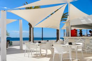 a restaurant with white tables and chairs and the ocean at Apartamentos Vibra Jabeque Soul-3SUP in Ibiza Town