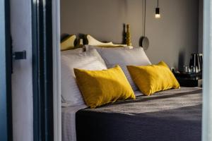 1 dormitorio con 1 cama con almohadas amarillas en Aethra Boutique Rooms en Nauplia
