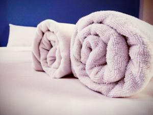 a pile of towels sitting on top of a bed at Beerapan Hotel in Bangkok