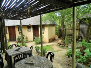 a patio with a table and chairs and a house at Kruger Inn Backpackers in Marloth Park