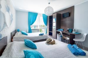 a bedroom with two beds with blue pillows and a desk at Dworek Karwia u Ewy Wiosenna 10 in Karwia