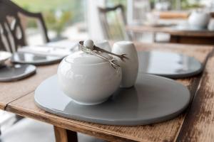 a wooden table with a white bowl on a plate at The Dartmouth Boutique B &B in Dartmouth