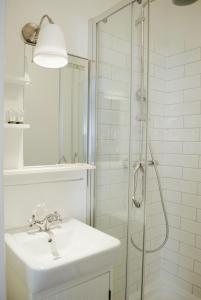 a white bathroom with a sink and a shower at Bursztynowy Domek in Międzywodzie