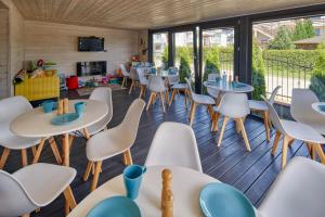 a restaurant with tables and chairs and windows at Dworek Karwia u Ewy Wiosenna 10 in Karwia