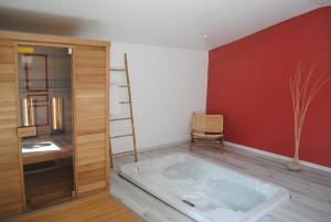 a bath tub in a room with a red wall at le Relais de la Cavayere - Chambres d'hôtes avec SPA & SAUNA Carcassonne - Parking privé ferme in Carcassonne +37 photos