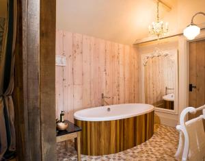 a bath tub in a bathroom with a wooden wall at The Fox by Greene King Inns in Bury Saint Edmunds