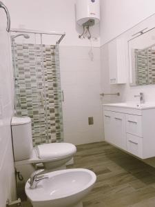 a white bathroom with a toilet and a sink at Il Cortile in Domus de Maria