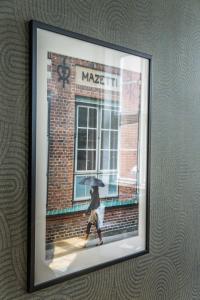 a framed picture of a person walking with an umbrella at The More Hotel Mazetti in Malmö