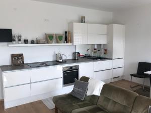 cocina con armarios blancos y sala de estar con sofá en Ferienwohnung Burgenblick mit Blick auf Riedenburg, en Riedenburg