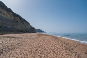 a sandy beach next to the ocean at Nikos & Vivi Studios in Perivolion