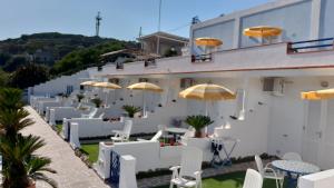 un bâtiment avec des chaises, des parasols et des tables blancs dans l'établissement Villa Flavia - Adults Only, à Ponza