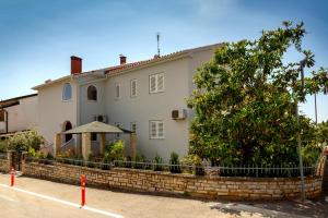 a white house with a fence in front of it at Apartment Erceg in Poreč
