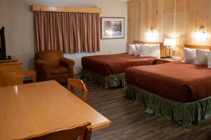 um quarto de hotel com duas camas e uma mesa em Aspen Village em Waterton Park