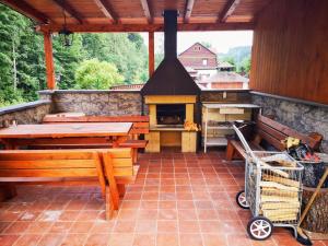 a patio with a grill and a table and benches at Apartmány Nad řekou in Svoboda nad Úpou