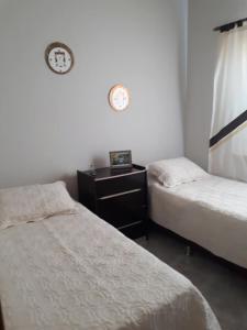 a room with two beds and a clock on the wall at Casa Em Capitolio in Capitólio