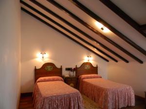 a bedroom with two beds and two lights on the wall at Pazo Carrasqueira in Ribadumia