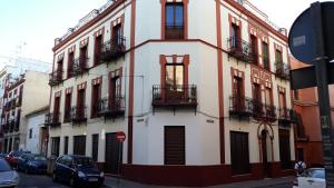 ein Gebäude mit Balkonen und Autos, die auf einer Straße geparkt sind in der Unterkunft Hub Hostel Seville in Sevilla
