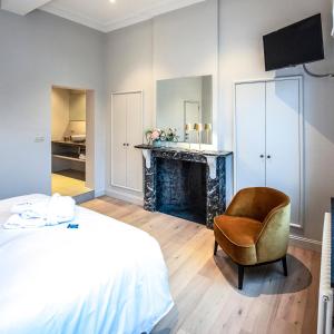 um quarto com uma cama, uma cadeira e uma lareira em Bed & Breakfast Jezuietenplein 21 em Oudenaarde