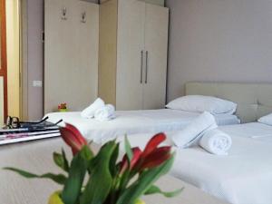 two beds in a hotel room with red flowers in the middle at Signature Idea hotel in Tirana