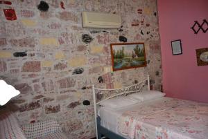 アイワルクにあるCunda Zehra Teyzenin Eviのレンガの壁の小さなベッドルーム(ベッド1台付)