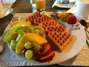 a plate of food with waffles and fruit on a table at Auberge À La Chouenne in La Malbaie