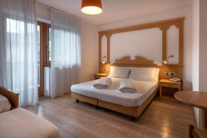 una camera con letto e testiera in legno di Hotel Europa a Pozza di Fassa