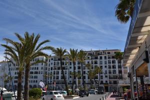 a large white building with palm trees on a street at Sea View Apartment in Manilva