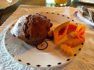 a plate with a muffin and fruit on a table at Auberge À La Chouenne in La Malbaie