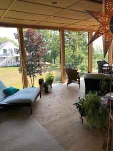 a screened in porch with a couch and chairs at Auberge À La Chouenne in La Malbaie